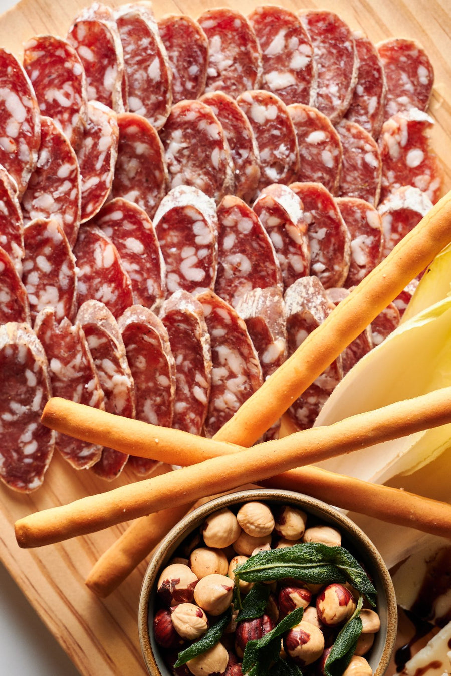 Salami, Olives, Hazelnuts, Breadsticks on a board