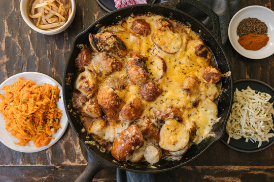 Finished raclette kit prepared in a cast iron pan with ingredients and salad surrounding